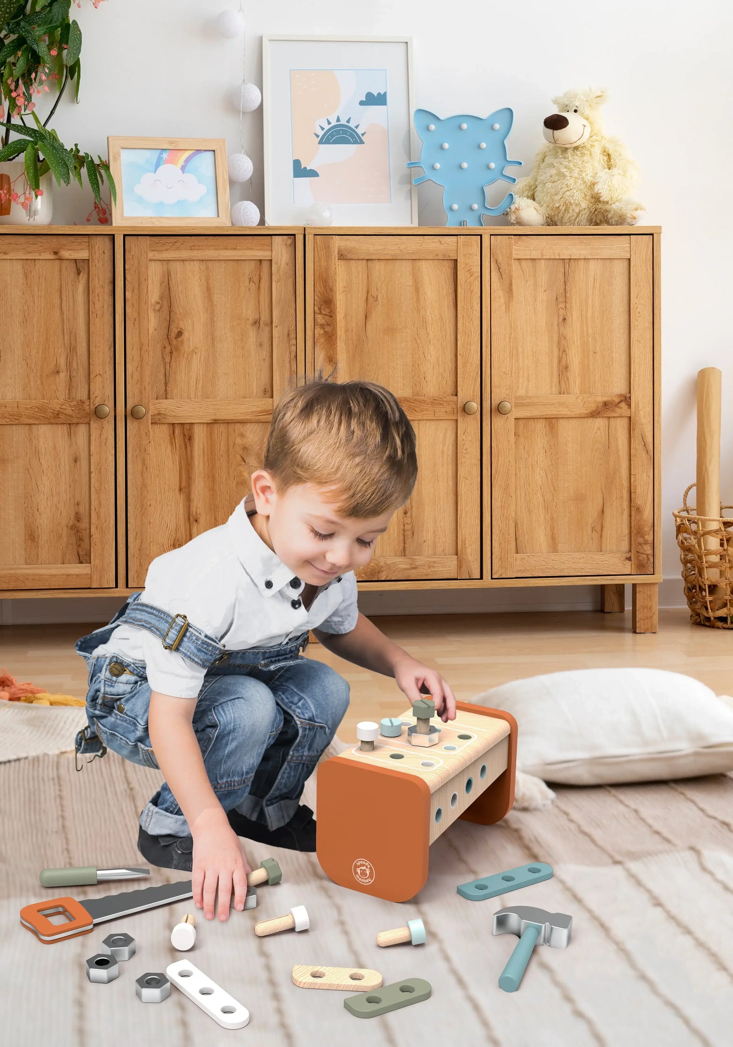 Child playing with wooden toy tools in cozy room with wooden cabinet and stuffed bear. Come see us at Awaken, Franklin, Tennessee