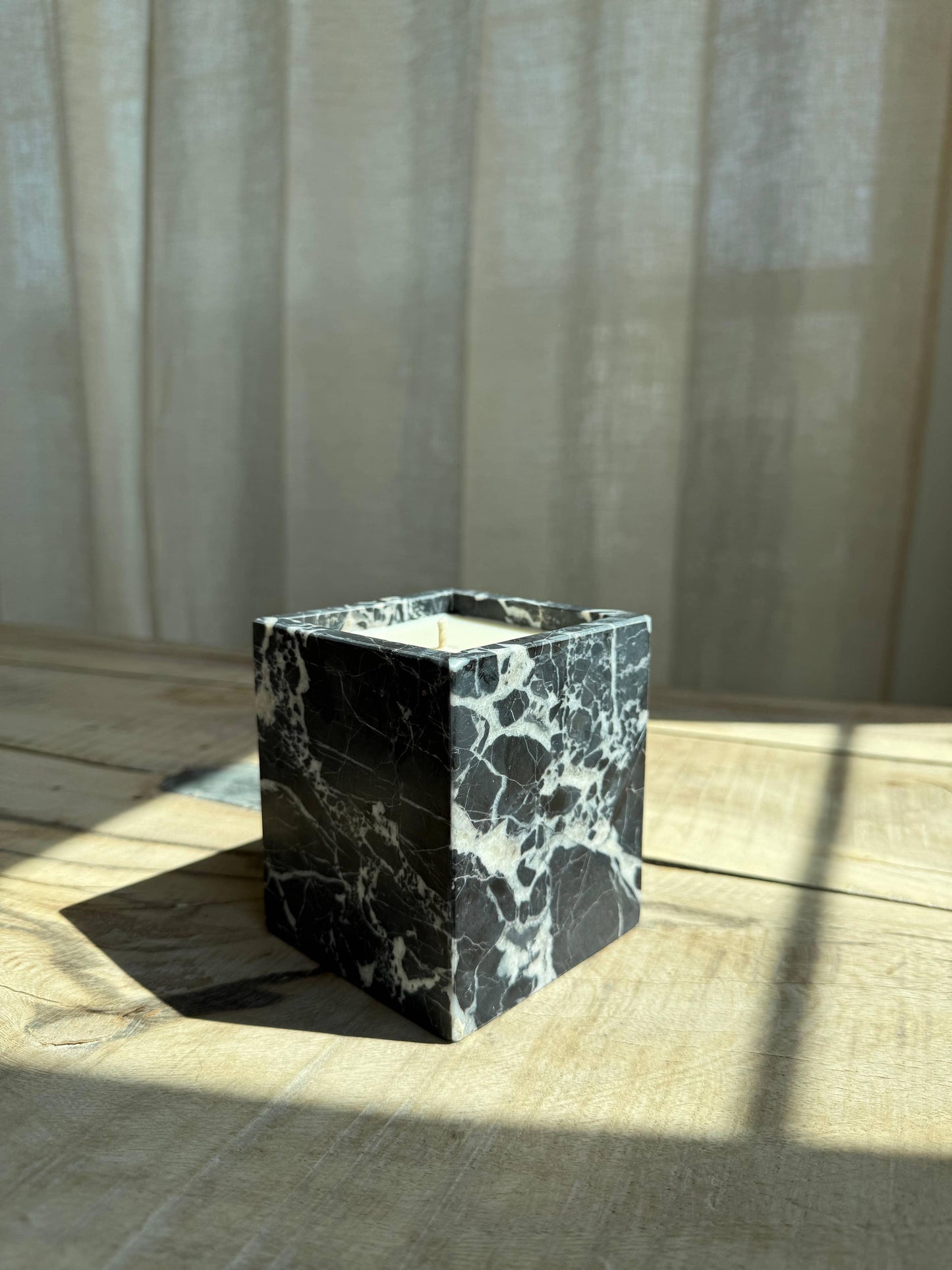Black and white marble candle holder on wooden table in soft sunlight, sheer curtains background. Come see us at Awaken, Franklin, Tennessee