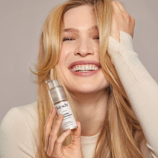 Smiling woman holding Kitsch Volumizing Shampoo, blonde hair, Come see us at Awaken, Franklin, Tennessee