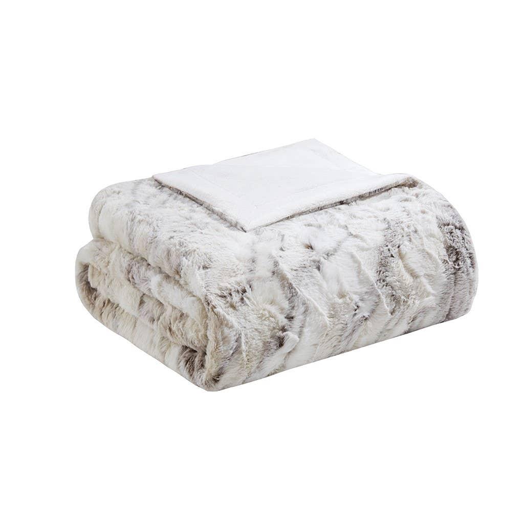 Folded white and gray faux fur blanket with soft plush backing on white background. Come see us at Awaken, Franklin, Tennessee