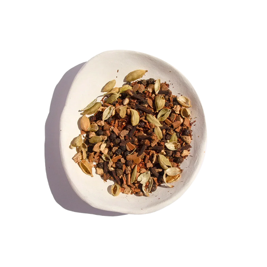 White bowl with mixed dried chai spices including cardamom, cloves, cinnamon, and peppercorns. Come see us at Awaken, Franklin, Tennessee
