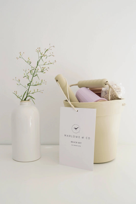 Marlowe & Co kids beach set in beige bucket with tools and white vase with delicate flower. Come see us at Awaken, Franklin, Tennessee