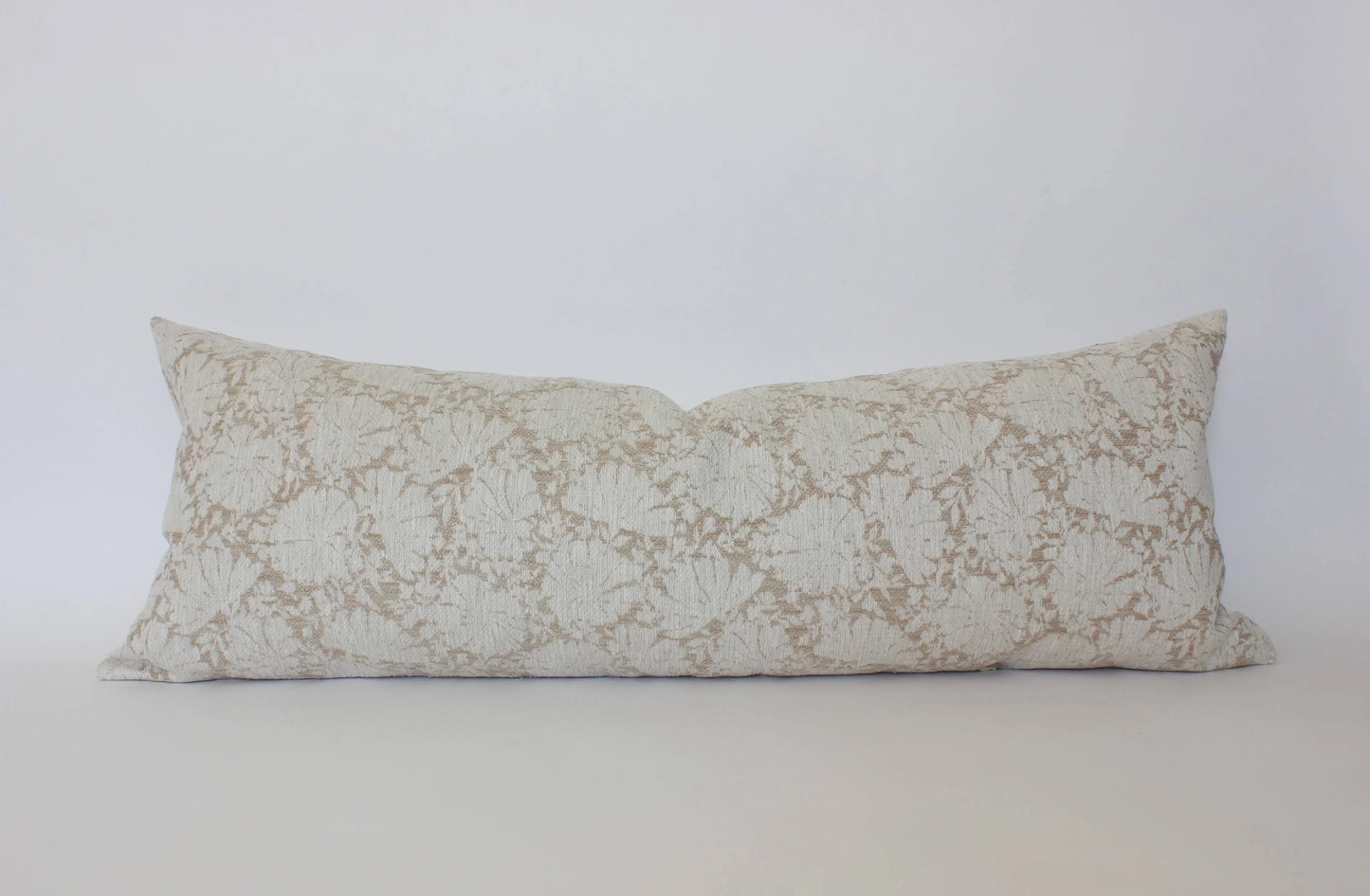 Long lumbar pillow with beige floral pattern on white background. Come see us at Awaken, Franklin, Tennessee