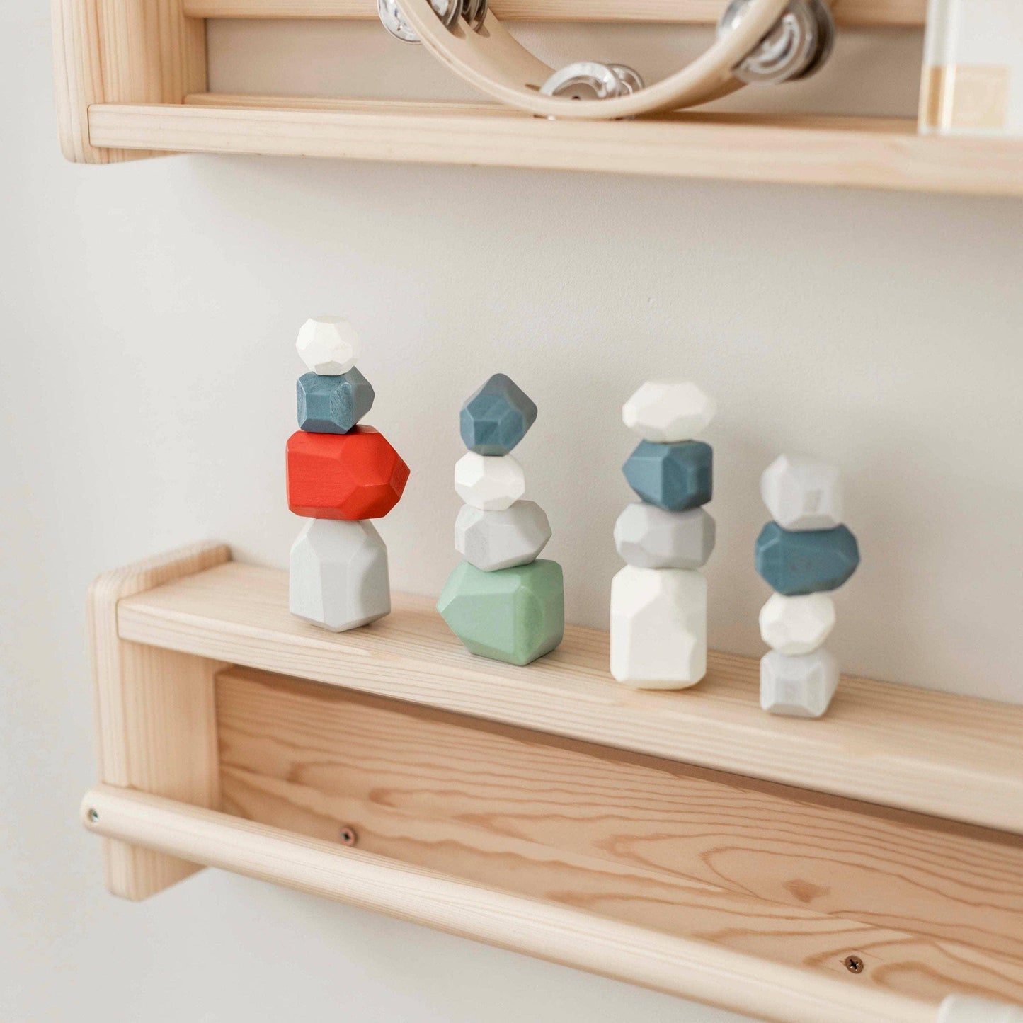 Stacked colorful wooden balancing rocks on a light wood shelf in minimalist decor. Come see us at Awaken, Franklin, Tennessee