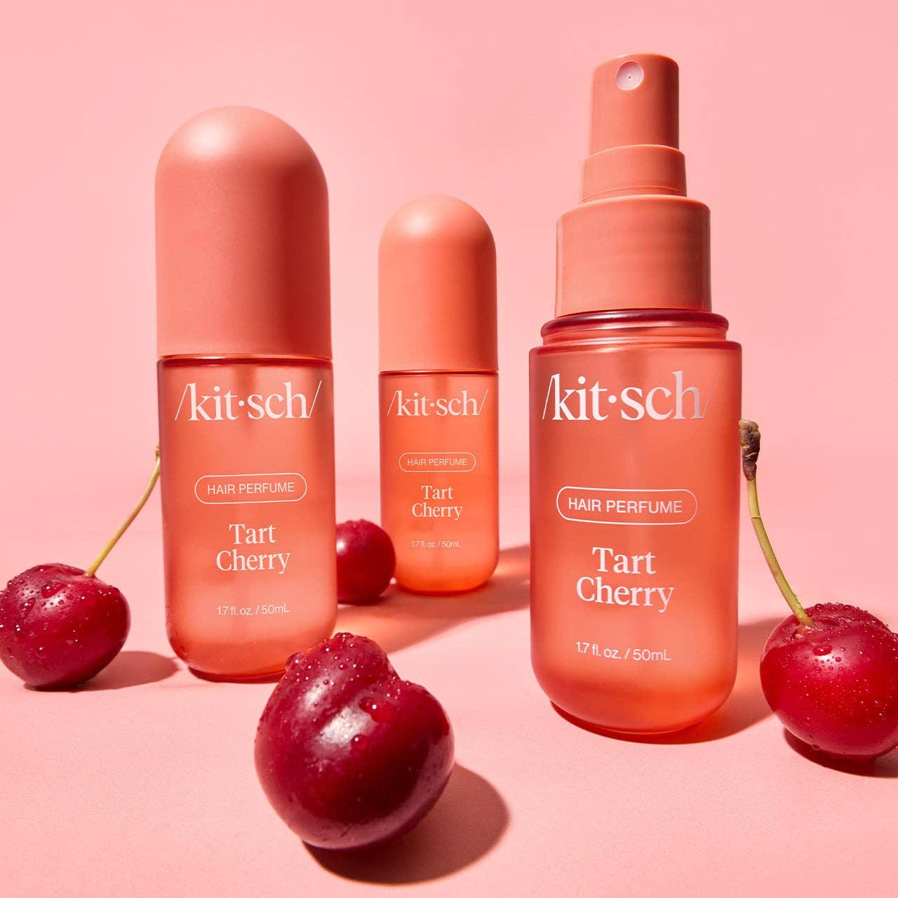 Kitsch Tart Cherry hair perfume bottles with fresh cherries on pink background. Come see us at Awaken, Franklin, Tennessee