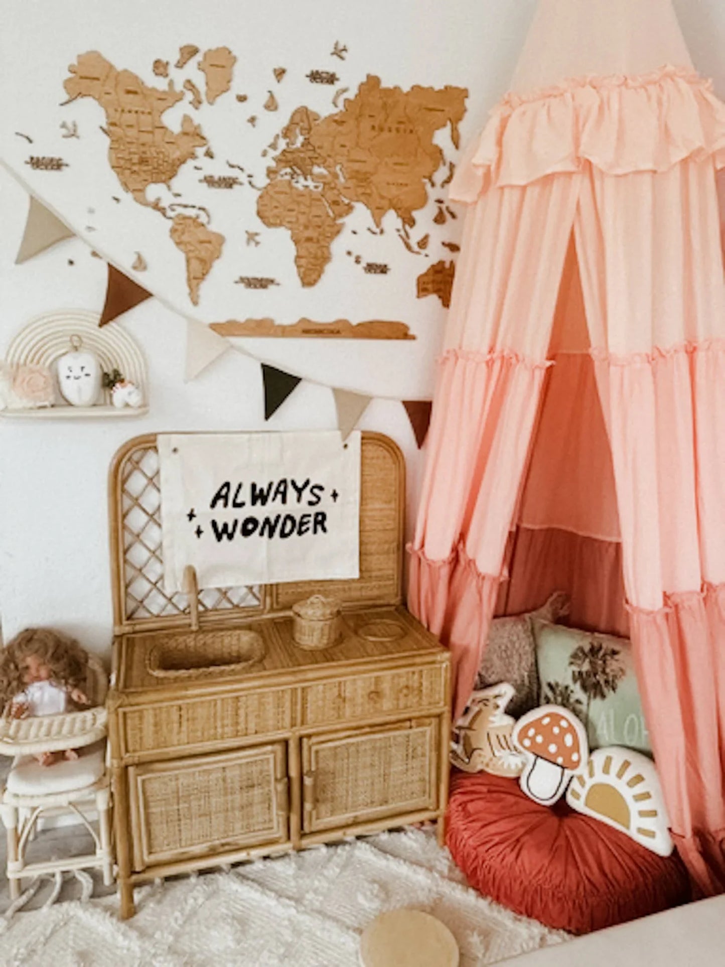Cozy kids playroom with wooden world map, pink canopy tent, rattan kitchen set, and 'Always Wonder' sign. Come see us at Awaken, Franklin, Tennessee