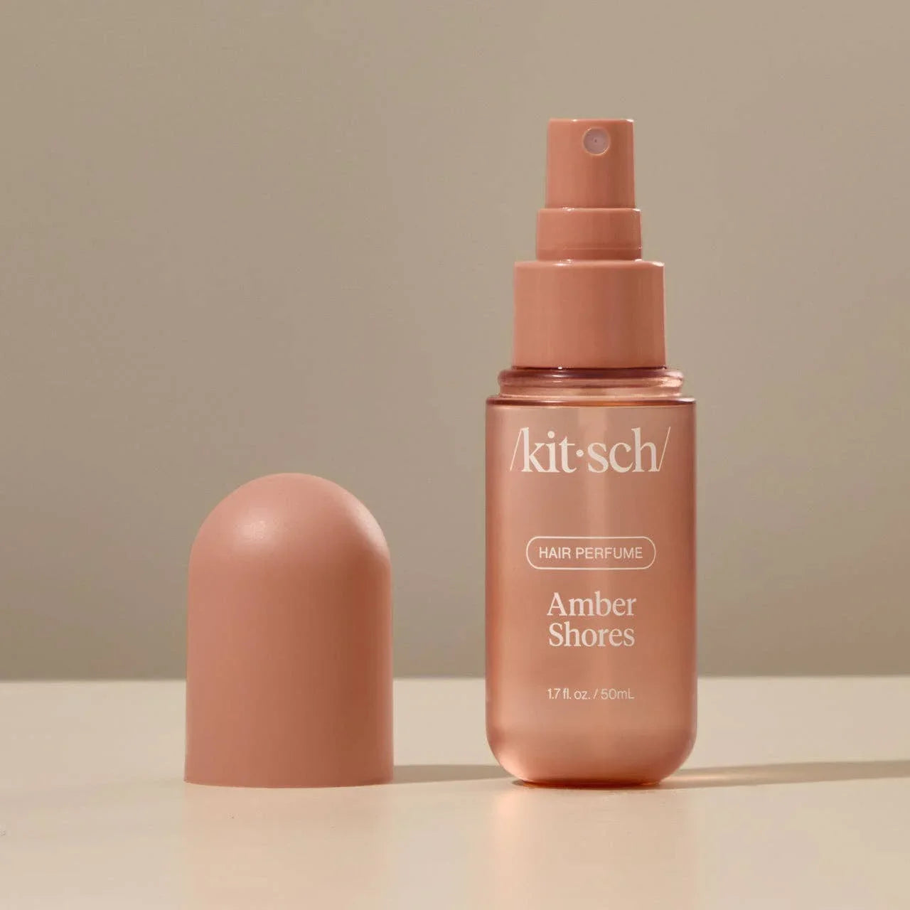 Kitsch Amber Shores hair perfume spray bottle and cap on beige background. Come see us at Awaken, Franklin, Tennessee