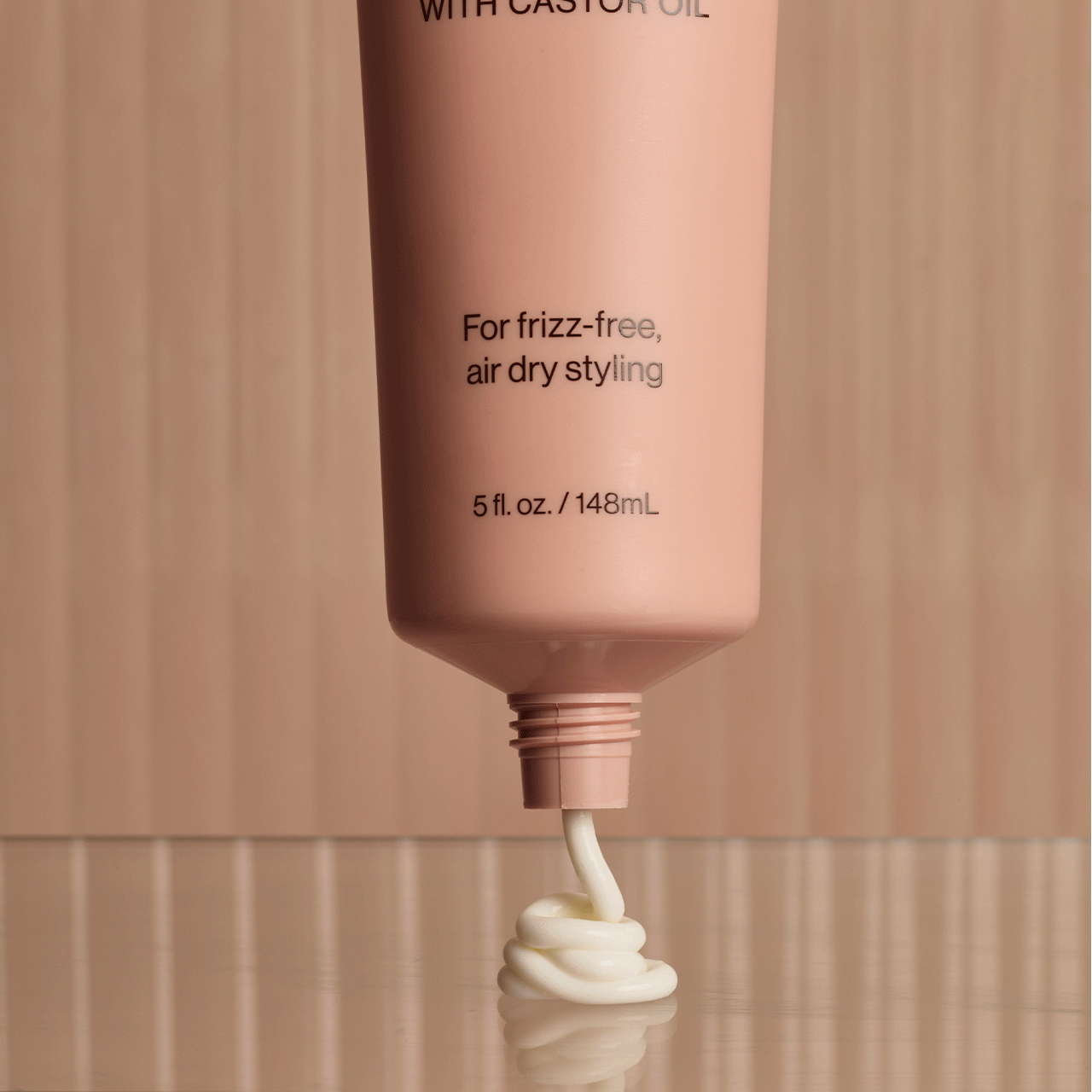 Pink tube dispensing cream for frizz-free air dry styling on reflective surface. Come see us at Awaken, Franklin, Tennessee