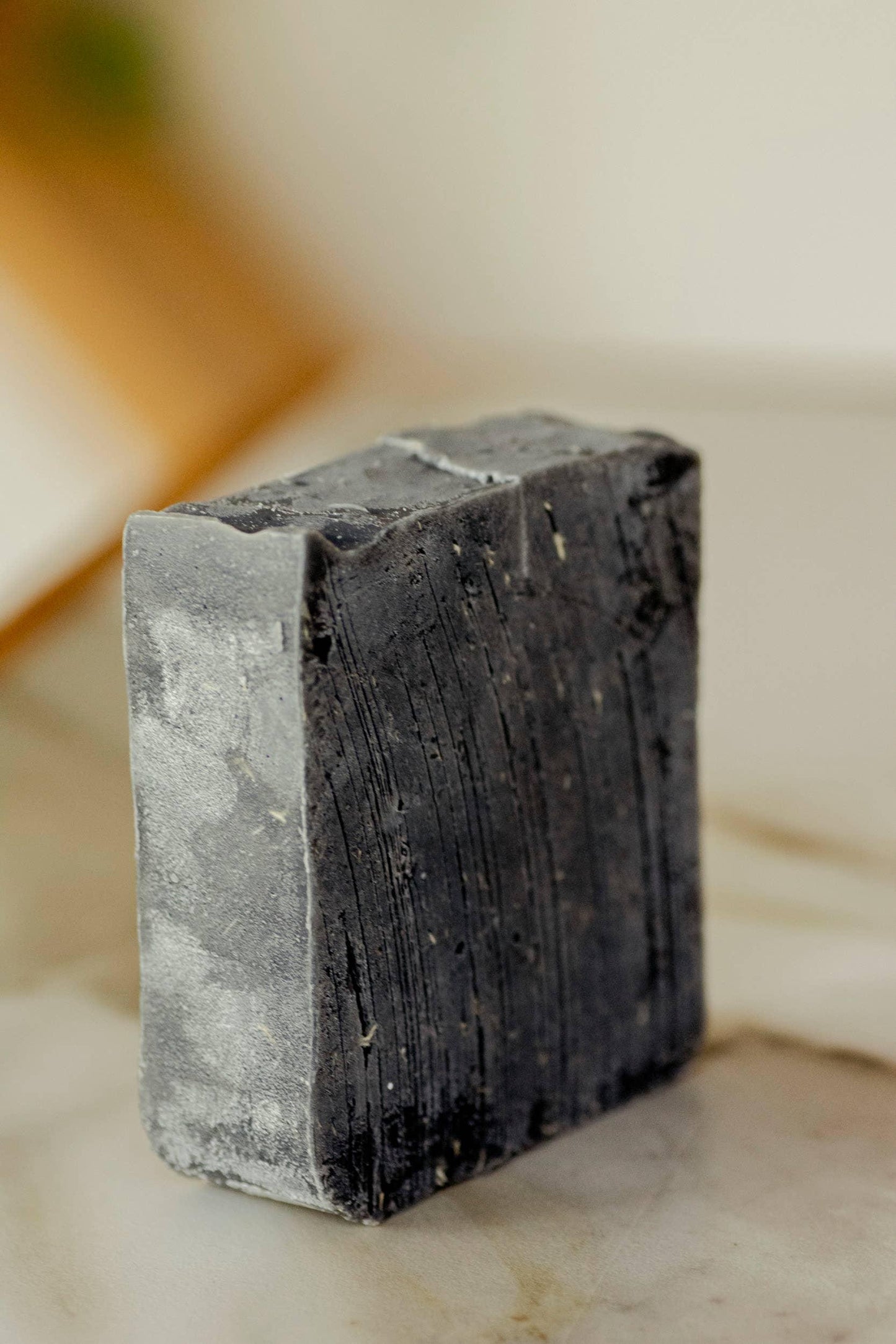 Close-up of textured charcoal black soap bar on marble surface Come see us at Awaken, Franklin, Tennessee