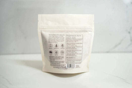 Back of Mushroom Multi supplement bag with ingredients and benefits listed on white marble surface, Come see us at Awaken, Franklin, Tennessee