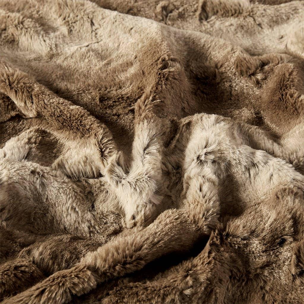 Soft, luxurious brown and beige faux fur blanket with textured folds, cozy home decor. Come see us at Awaken, Franklin, Tennessee