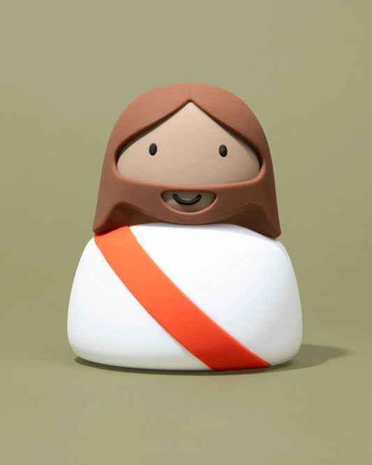 Cute modern Jesus figurine in white with orange sash on green background. Come see us at Awaken, Franklin, Tennessee