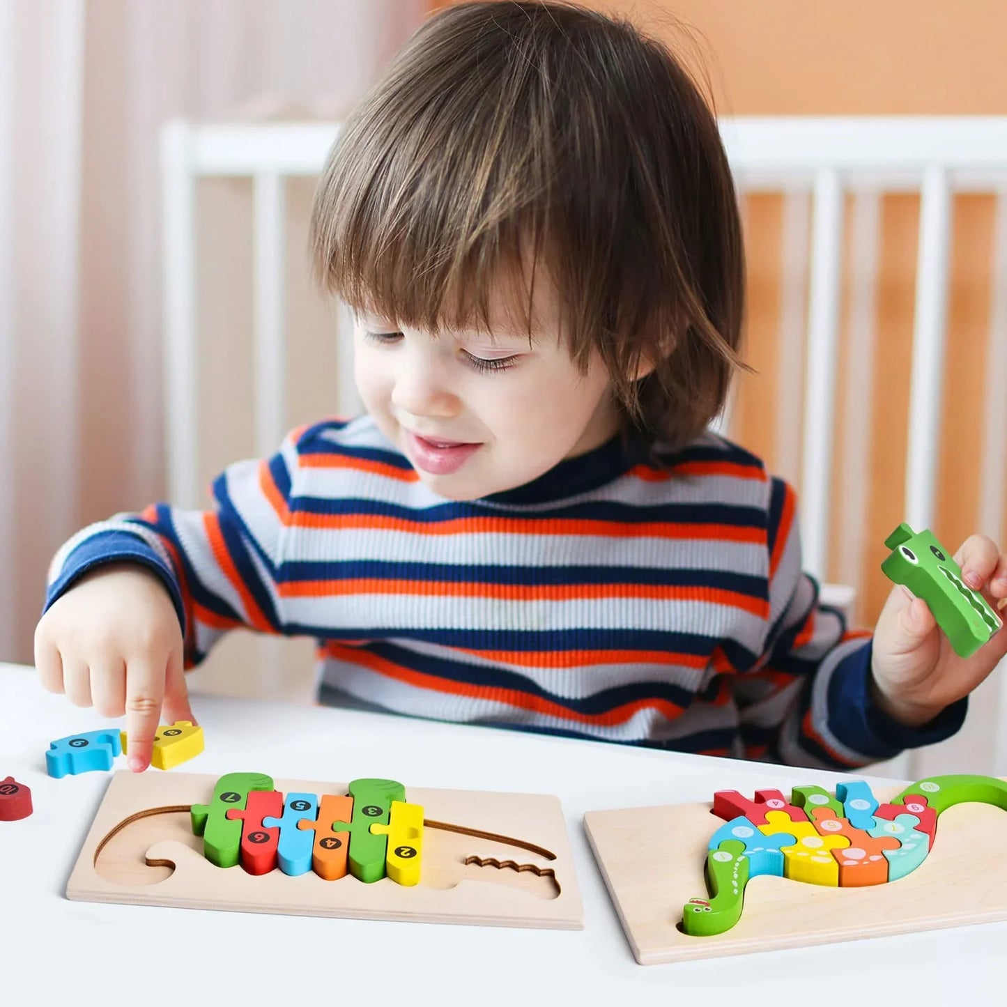 Child playing with colorful wooden animal puzzles at table, striped shirt, indoor playtime. Come see us at Awaken, Franklin, Tennessee