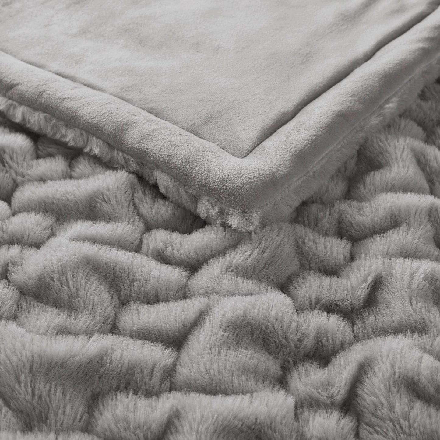 Soft grey faux fur blanket with plush edges on textured fur surface. Come see us at Awaken, Franklin, Tennessee
