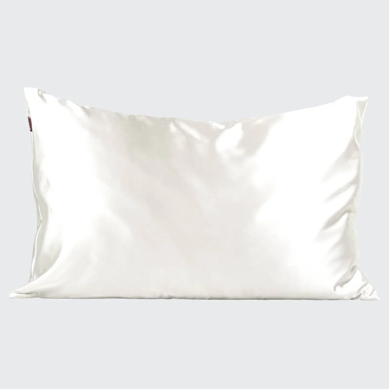 White satin pillow with smooth texture on light gray background, luxury bedding accessory. Come see us at Awaken, Franklin, Tennessee