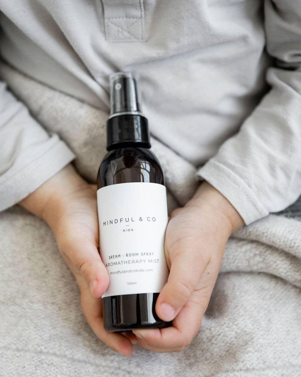 Child holding Mindful & Co Kids Dream Room Spray aromatherapy mist bottle. Come see us at Awaken, Franklin, Tennessee