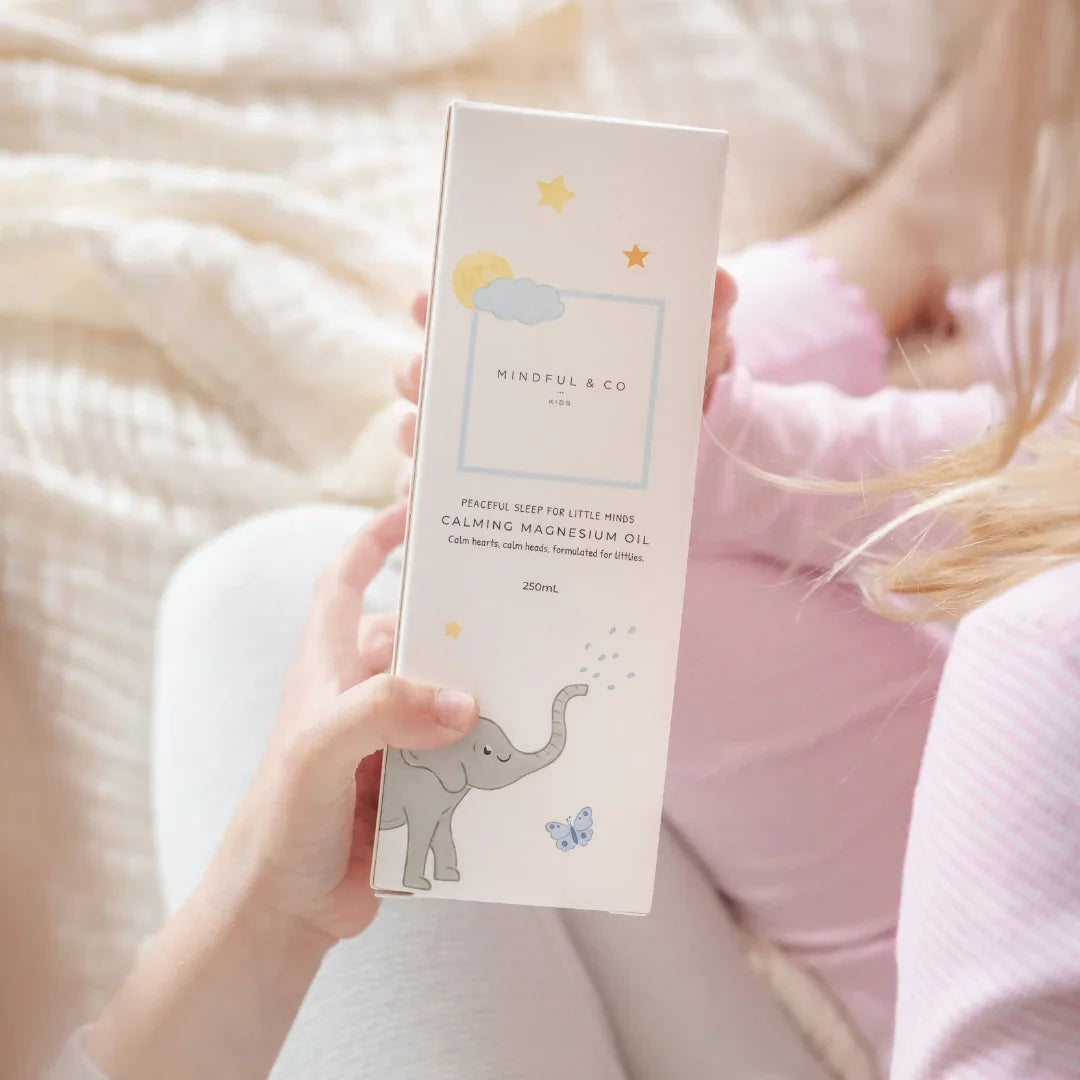 Child holding Mindful & Co Kids Calming Magnesium Oil box with elephant design, soothing sleep aid. Come see us at Awaken, Franklin, Tennessee
