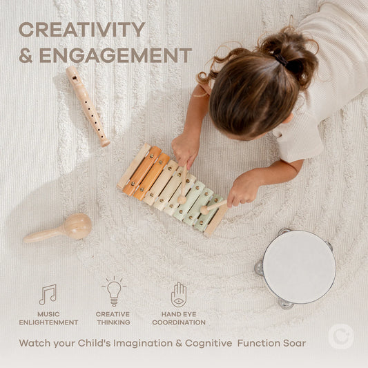 Child playing xylophone and tambourine on beige rug promoting creativity and engagement. Come see us at Awaken, Franklin, Tennessee