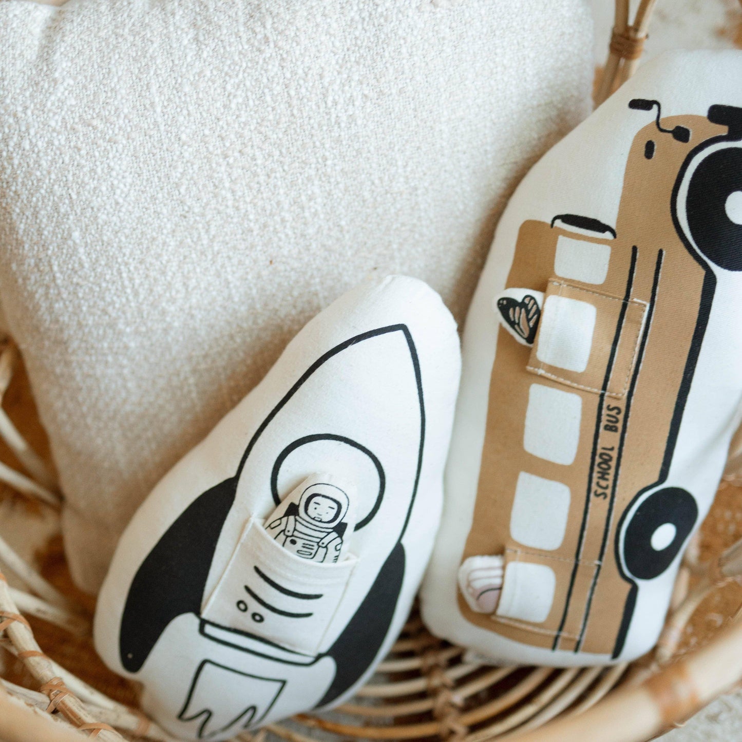 Rocket and school bus shaped soft toys in a woven basket on soft fabric background. Come see us at Awaken, Franklin, Tennessee