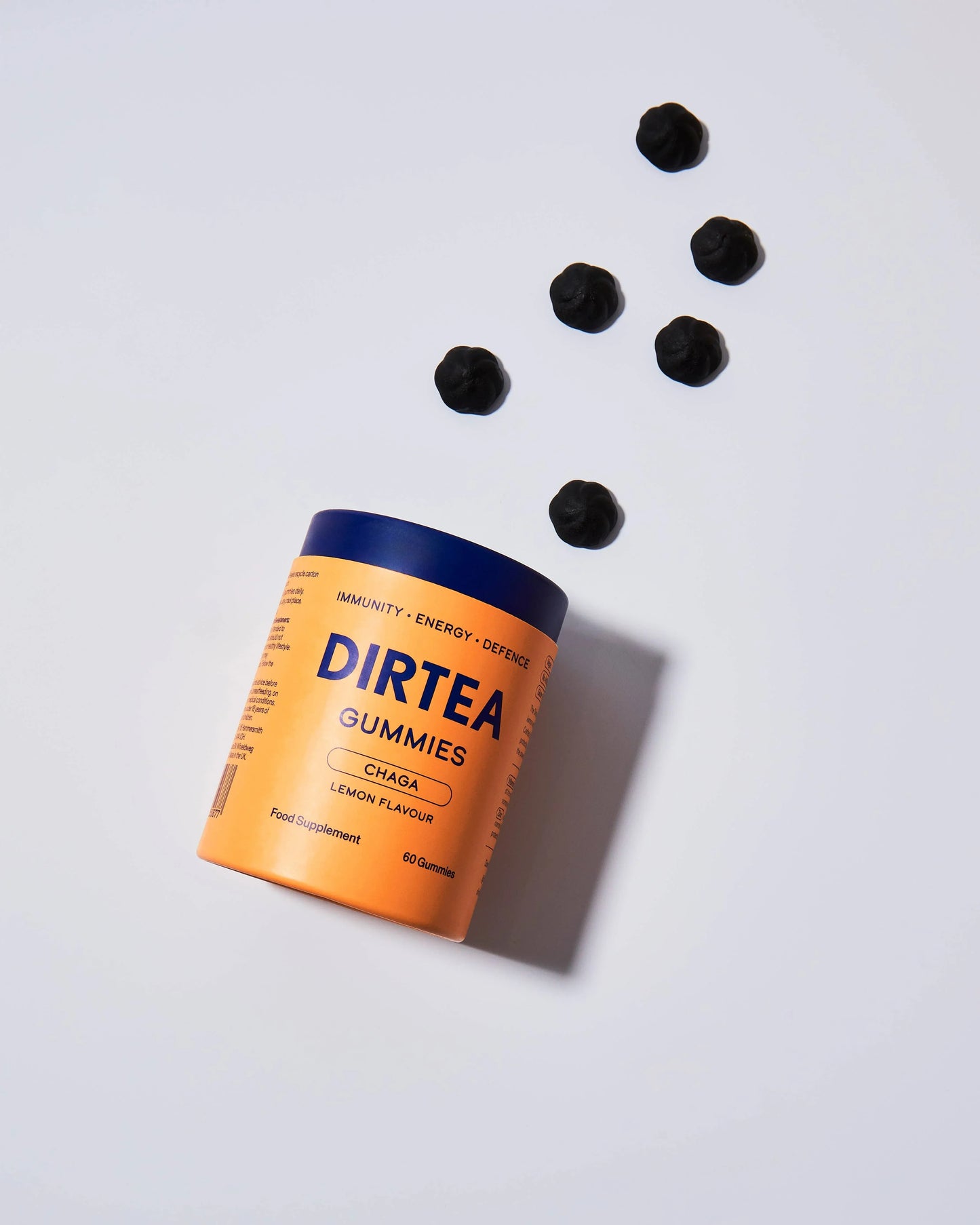 DIRTEA Chaga lemon flavor immunity gummies container with black gummies scattered, clean white background. Come see us at Awaken, Franklin, Tennessee
