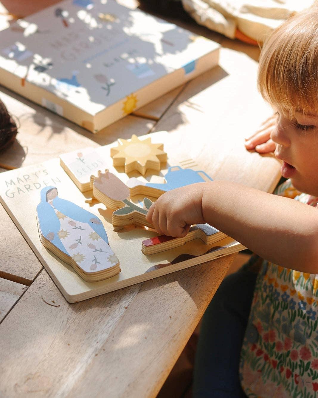 Toddler playing with wooden garden puzzle pieces of Mary, flower, sun on table. Come see us at Awaken, Franklin, Tennessee