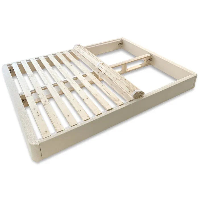 Wooden bed frame with slats and padded beige fabric sides, modern minimalist design. Come see us at Awaken, Franklin, Tennessee