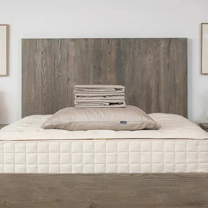 Neutral modern bed with quilted mattress, beige pillow, folded bedding, wooden headboard. Come see us at Awaken, Franklin, Tennessee