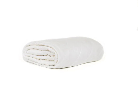 Folded white comforter on white background, soft bedding product. Come see us at Awaken, Franklin, Tennessee