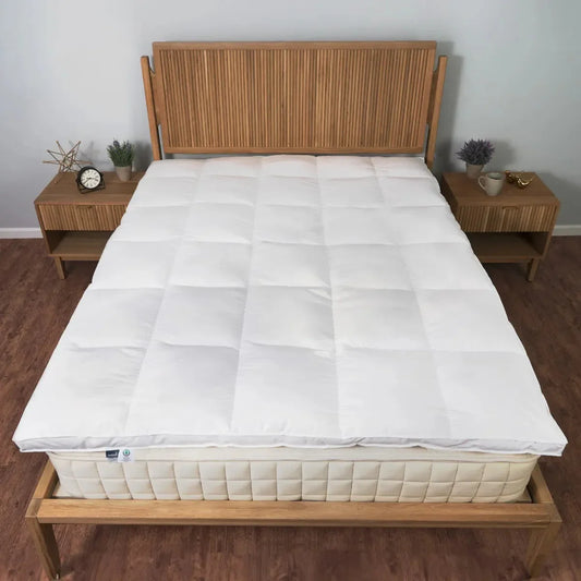 White quilted mattress topper on beige mattress with wooden slatted headboard and matching nightstands. Come see us at Awaken, Franklin, Tennessee