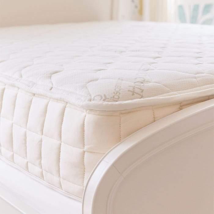 Close-up of a plush white mattress on a white bed frame in a bright bedroom. Come see us at Awaken, Franklin, Tennessee