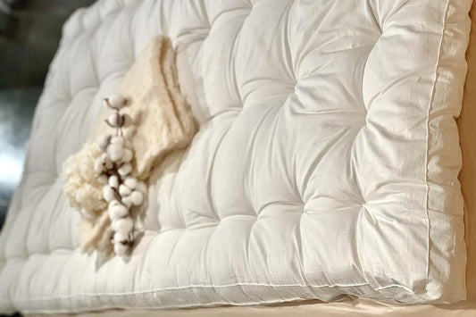 Plush white tufted mattress with soft beige knit blanket and cotton stems, cozy bedding. Come see us at Awaken, Franklin, Tennessee