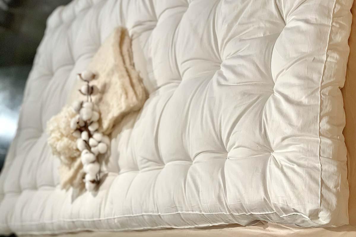 White tufted mattress topper with beige knit blanket and cotton stems, soft bedding. Come see us at Awaken, Franklin, Tennessee