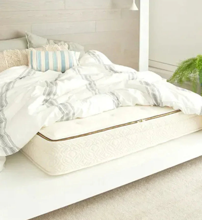 White mattress with quilted pattern under white and gray striped comforter on bed frame with pillows. Come see us at Awaken, Franklin, Tennessee