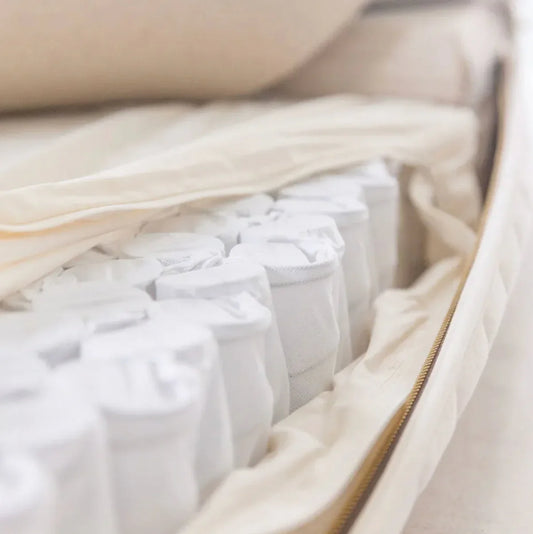 Close-up of white pocketed coils inside beige mattress with zipper cover. Come see us at Awaken, Franklin, Tennessee