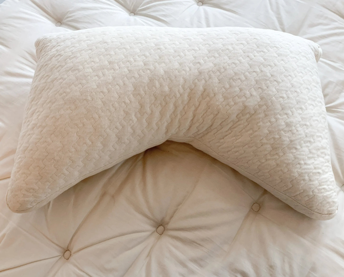 Cream-colored ergonomic pillow with textured pattern on tufted mattress, Come see us at Awaken, Franklin, Tennessee