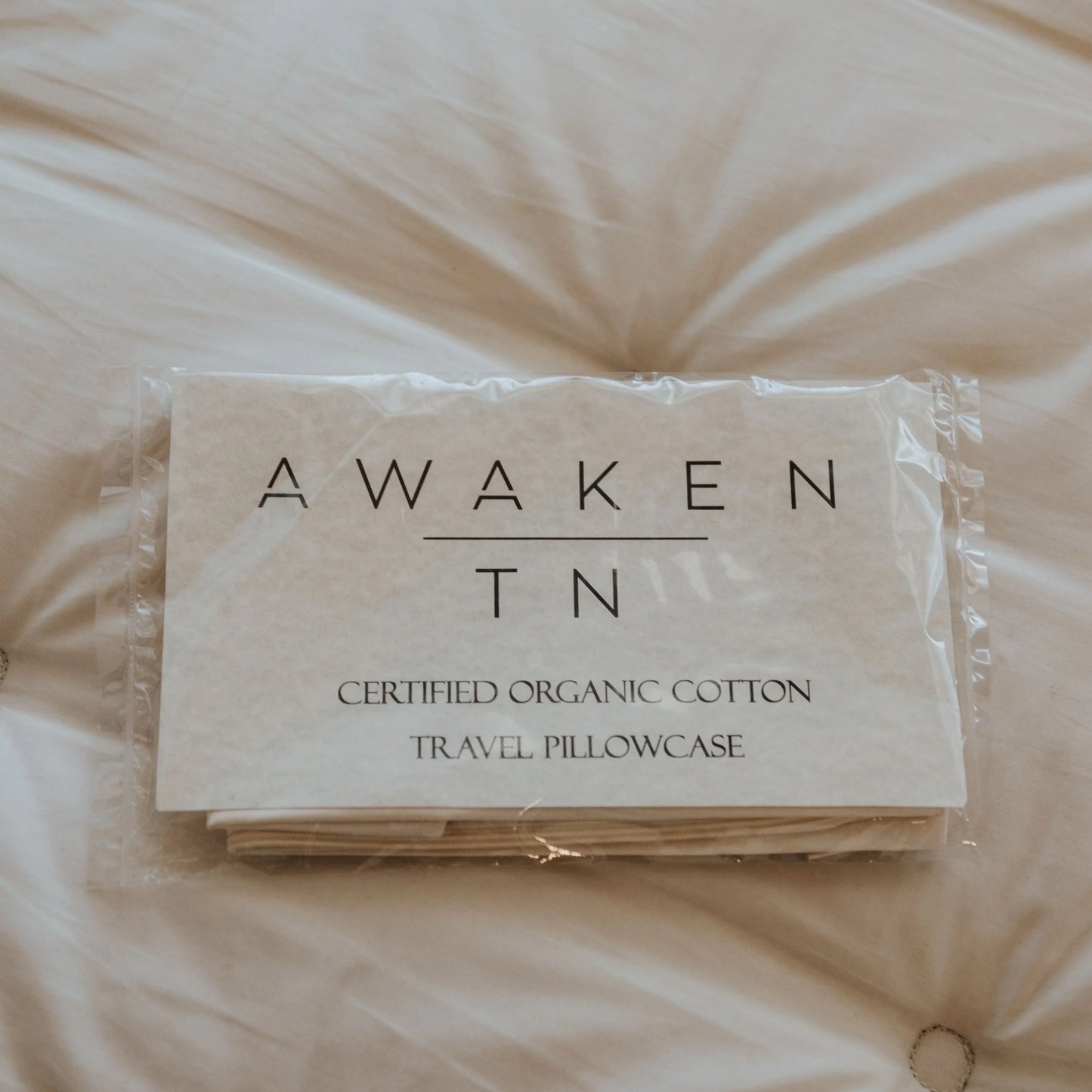Packaged Awaken TN certified organic cotton travel pillowcase on beige fabric. Come see us at Awaken, Franklin, Tennessee