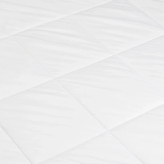 Close-up of white quilted mattress pad with diamond pattern for bedding comfort. Come see us at Awaken, Franklin, Tennessee