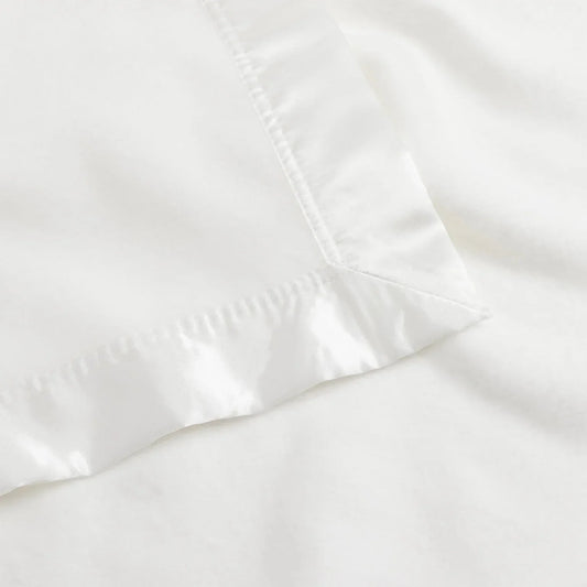 White satin-trimmed blanket corner, luxury bedding. Come see us at Awaken, Franklin, Tennessee.