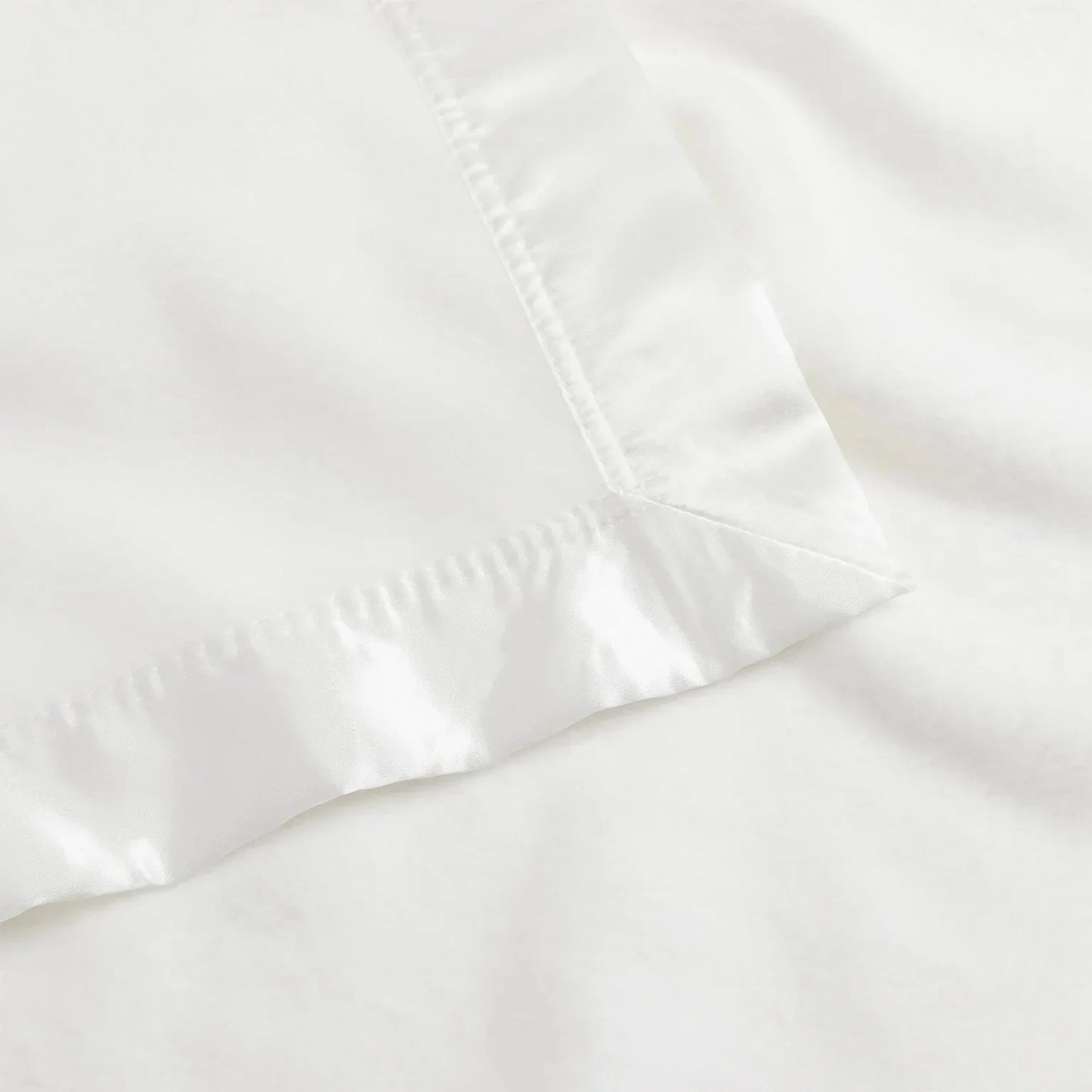 Close-up of white silky satin blanket edge on soft fabric surface. Come see us at Awaken, Franklin, Tennessee