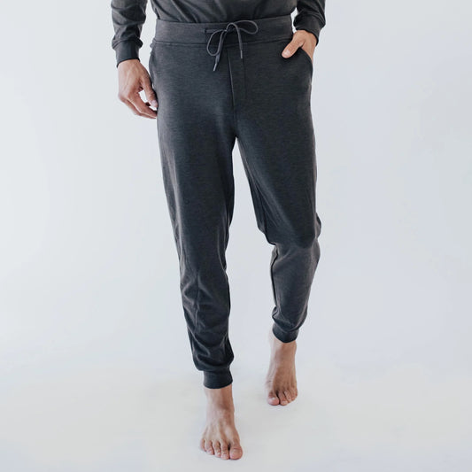 Man wearing dark gray jogger pants with drawstring, standing barefoot on white background. Come see us at Awaken, Franklin, Tennessee