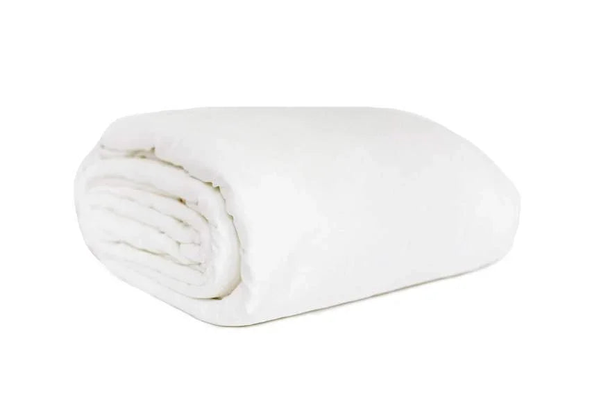 Folded white blanket on a white background for cozy home comfort. Come see us at Awaken, Franklin, Tennessee