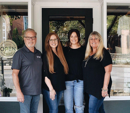 Group of four smiling people standing outside a shop with open sign. Come see us at Awaken, Franklin, Tennessee