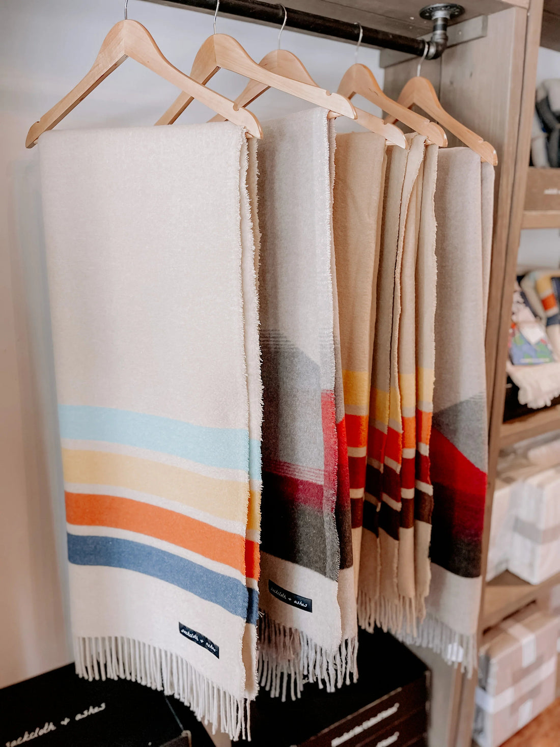 Colorful striped blankets hanging on wooden hangers, Come see us at Awaken, Franklin, Tennessee