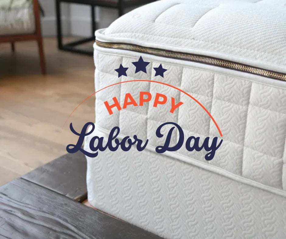 Close-up of a white mattress with Happy Labor Day text and stars overlaid, wooden floor background, Come see us at Awaken, Franklin, Tennessee