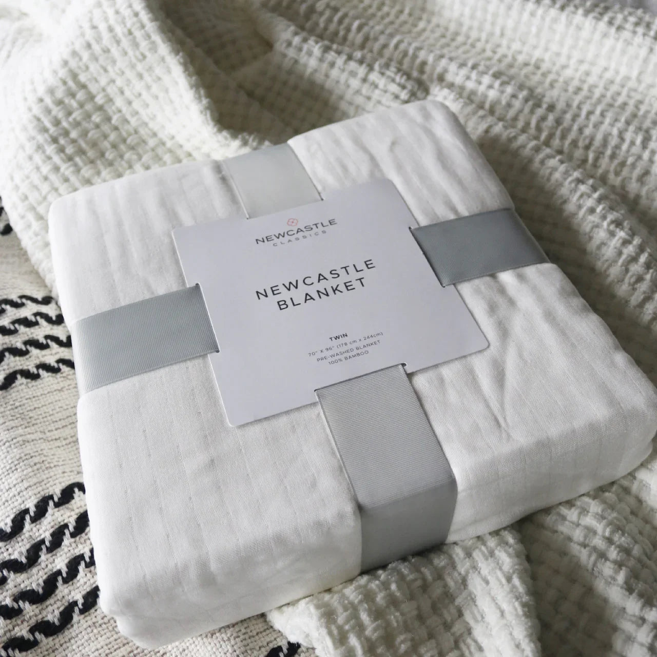 Newcastle bamboo blanket packaged on textured bedding, Come see us at Awaken, Franklin, Tennessee
