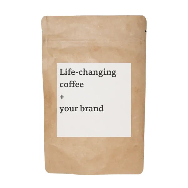 Brown coffee bag with label 'Life-changing coffee + your brand' on white background. Come see us at Awaken, Franklin, Tennessee