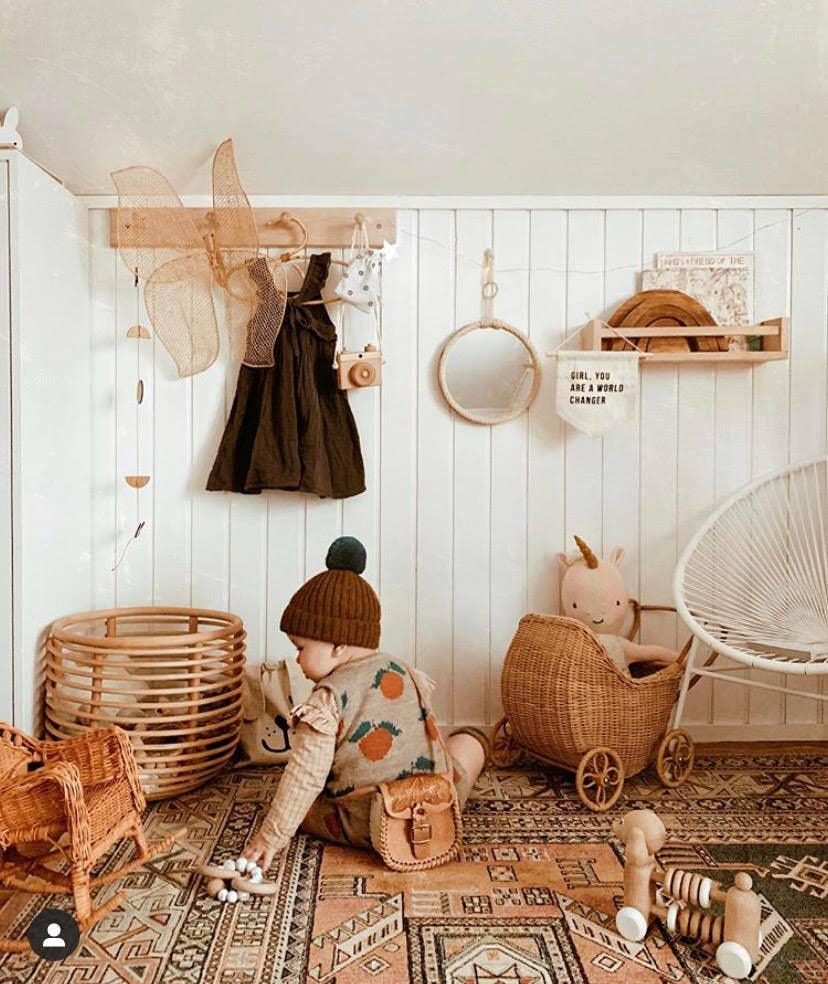 Boho nursery decor with toddler playing, wooden toys, rattan furniture, Come see us at Awaken, Franklin, Tennessee.
