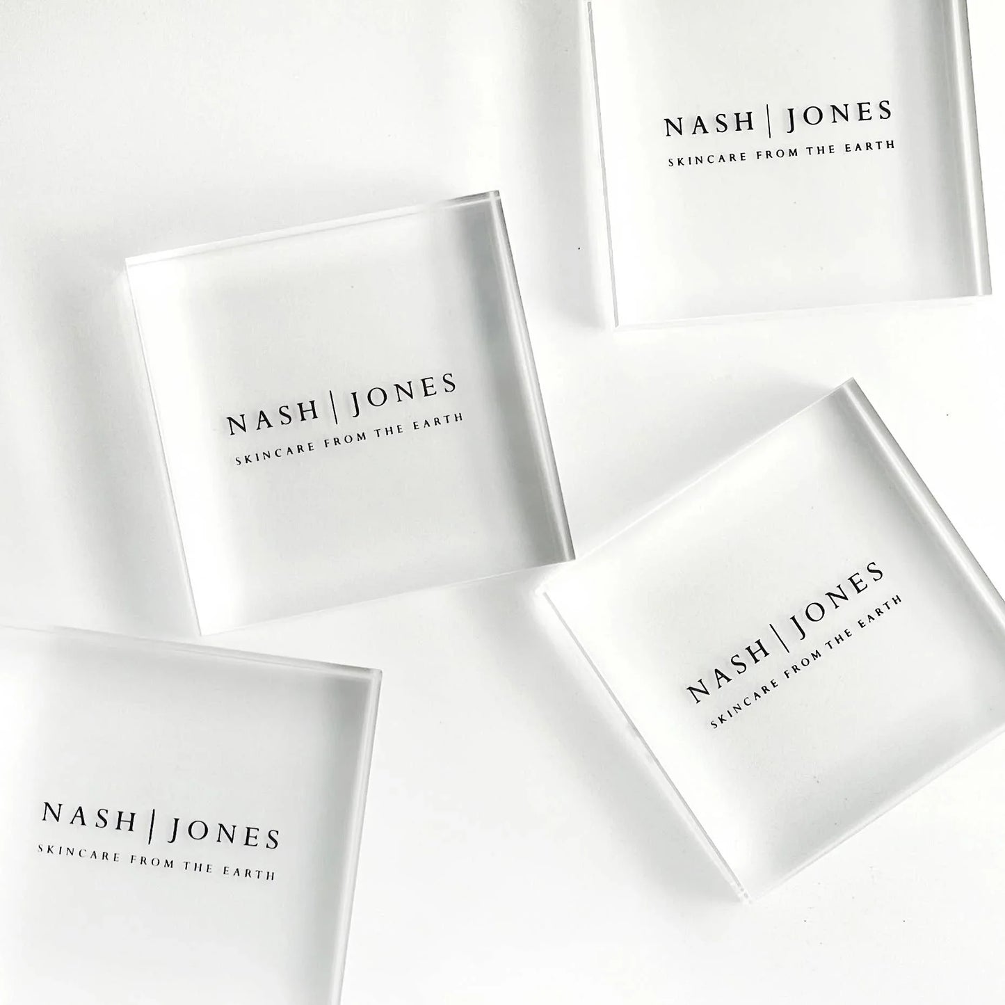 Nash | Jones skincare translucent square containers on white background, natural beauty products. Come see us at Awaken, Franklin, Tennessee