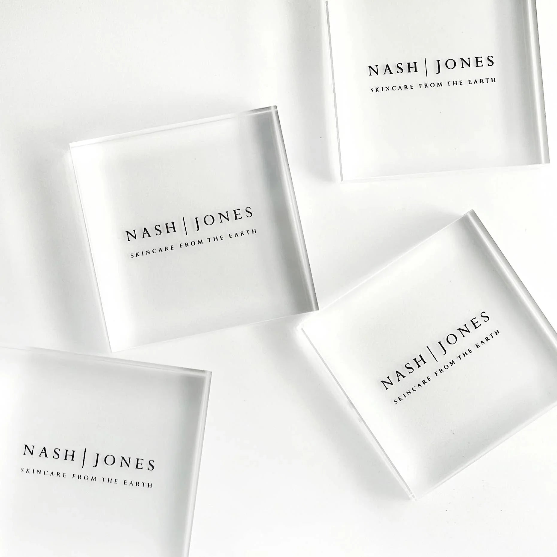 Nash | Jones skincare translucent square containers on white background, natural beauty products. Come see us at Awaken, Franklin, Tennessee