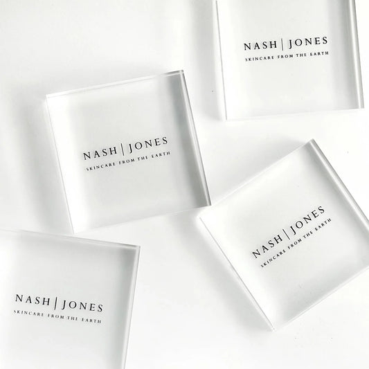 Nash | Jones skincare translucent square containers on white background, natural beauty products. Come see us at Awaken, Franklin, Tennessee